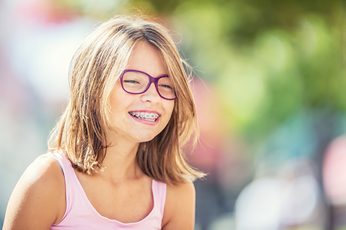 Little girl smiling with braces and glasses.